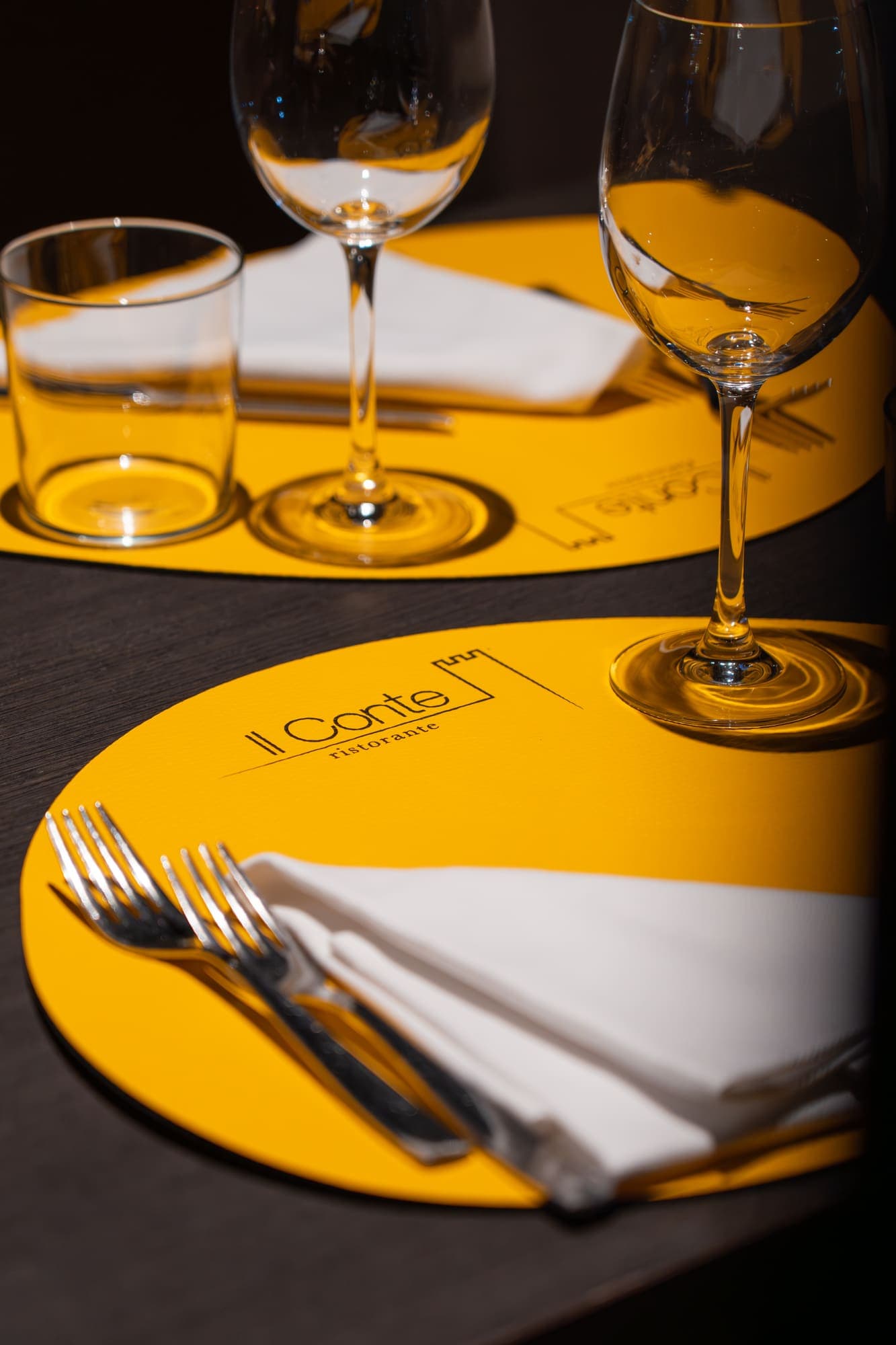 Tavolo apparecchiato con il logo Il Conte ristorante sul tovagliolo giallo